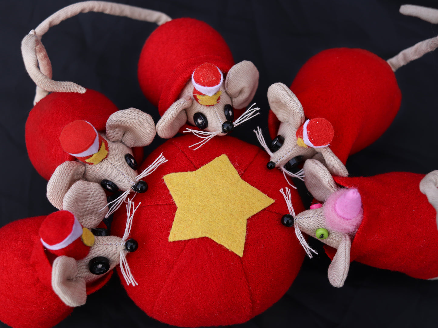 Decorative item with plush mice and a red ball featuring a yellow star on a dark background