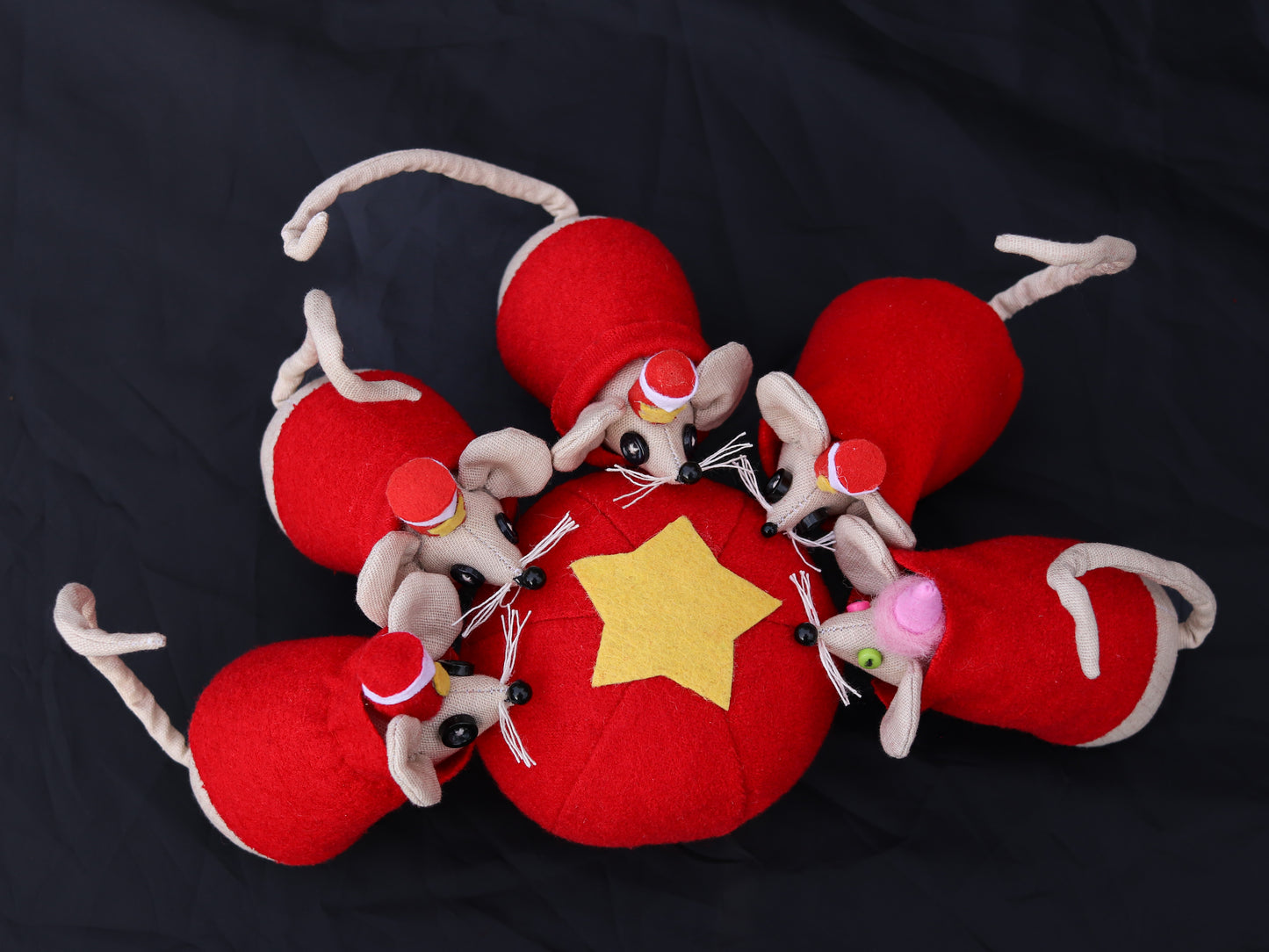 Decorative plush toy mice with red hats and a yellow star ball on a dark background