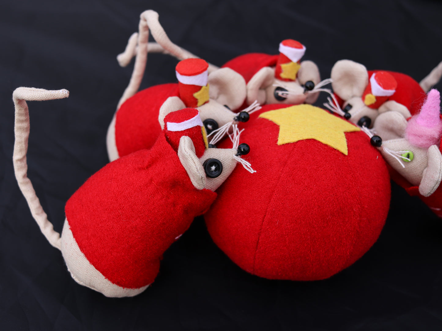 Red plush toy mice with a yellow star ball on a black background