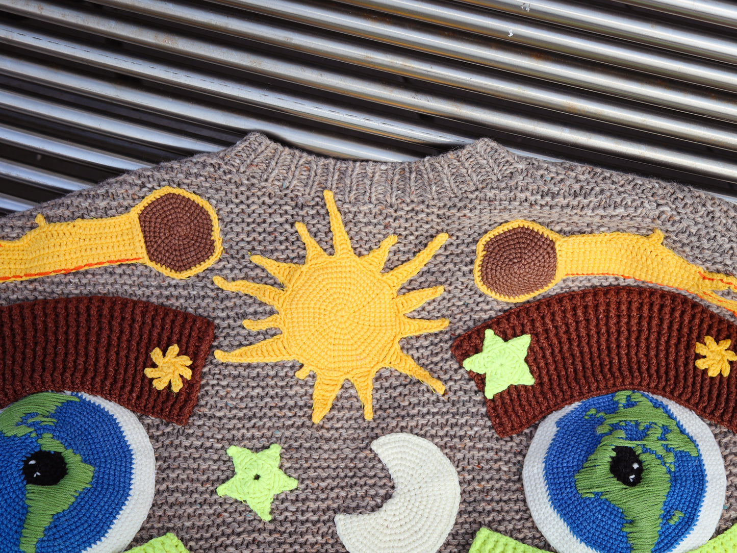 Textile with embroidered knit solar system design on a textured cardigan surface