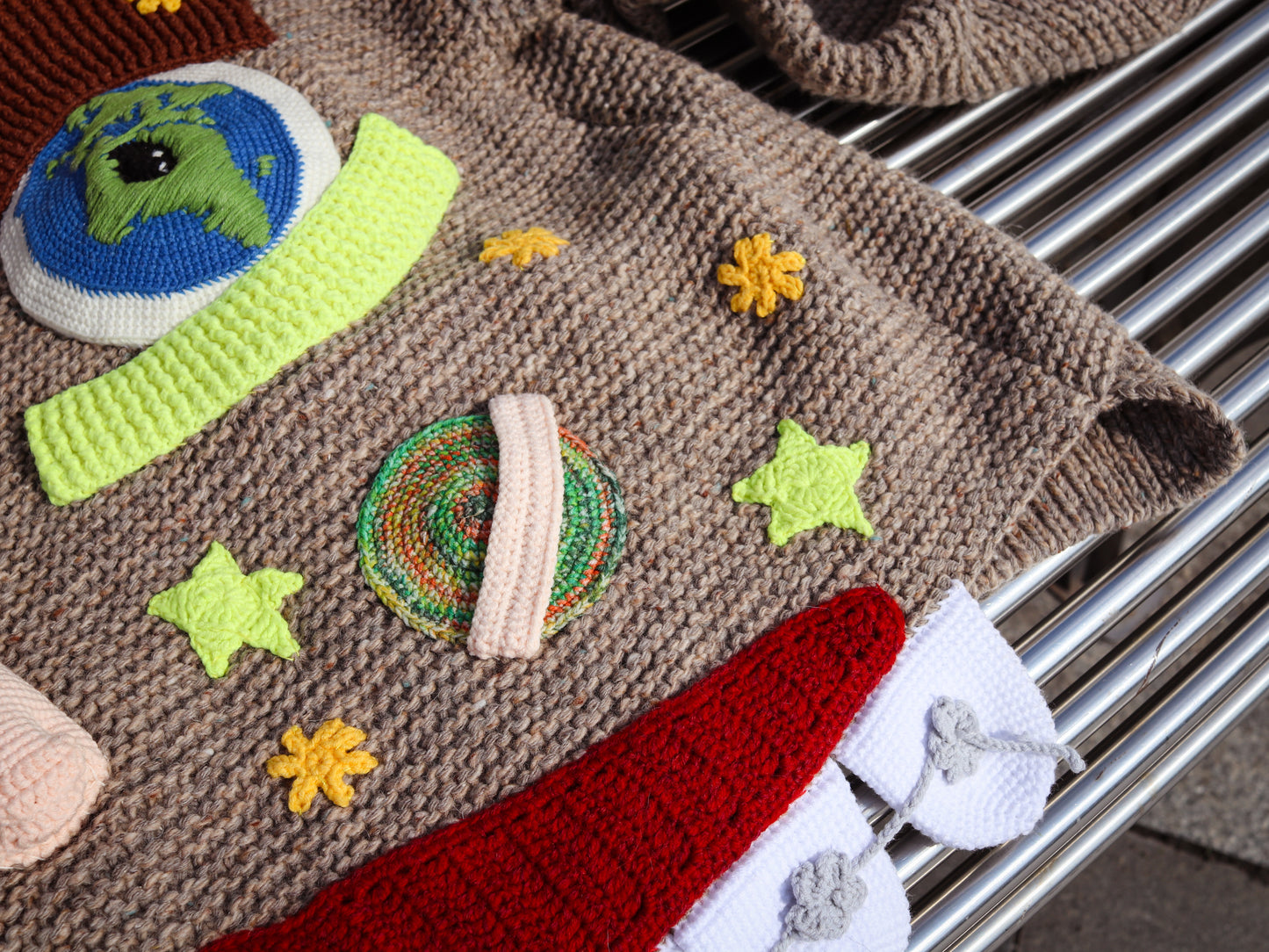 Knitted sweater with colorful patches on a metal surface