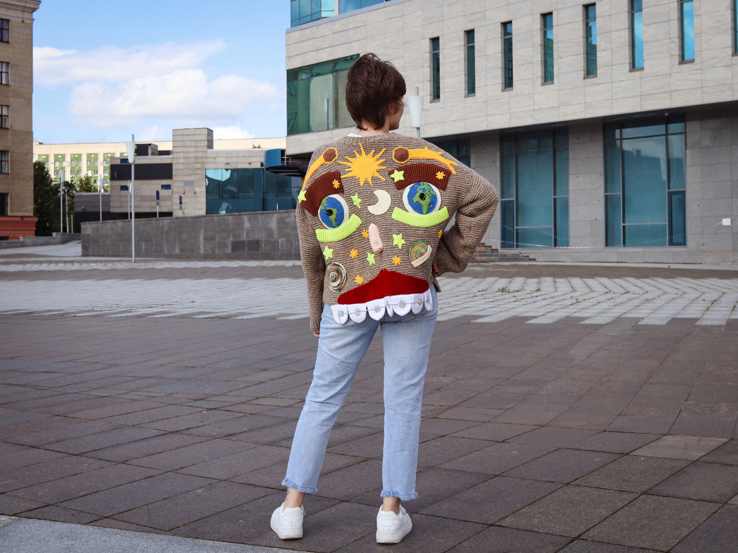 Person wearing a colorful cardigan with abstract designs in an urban setting