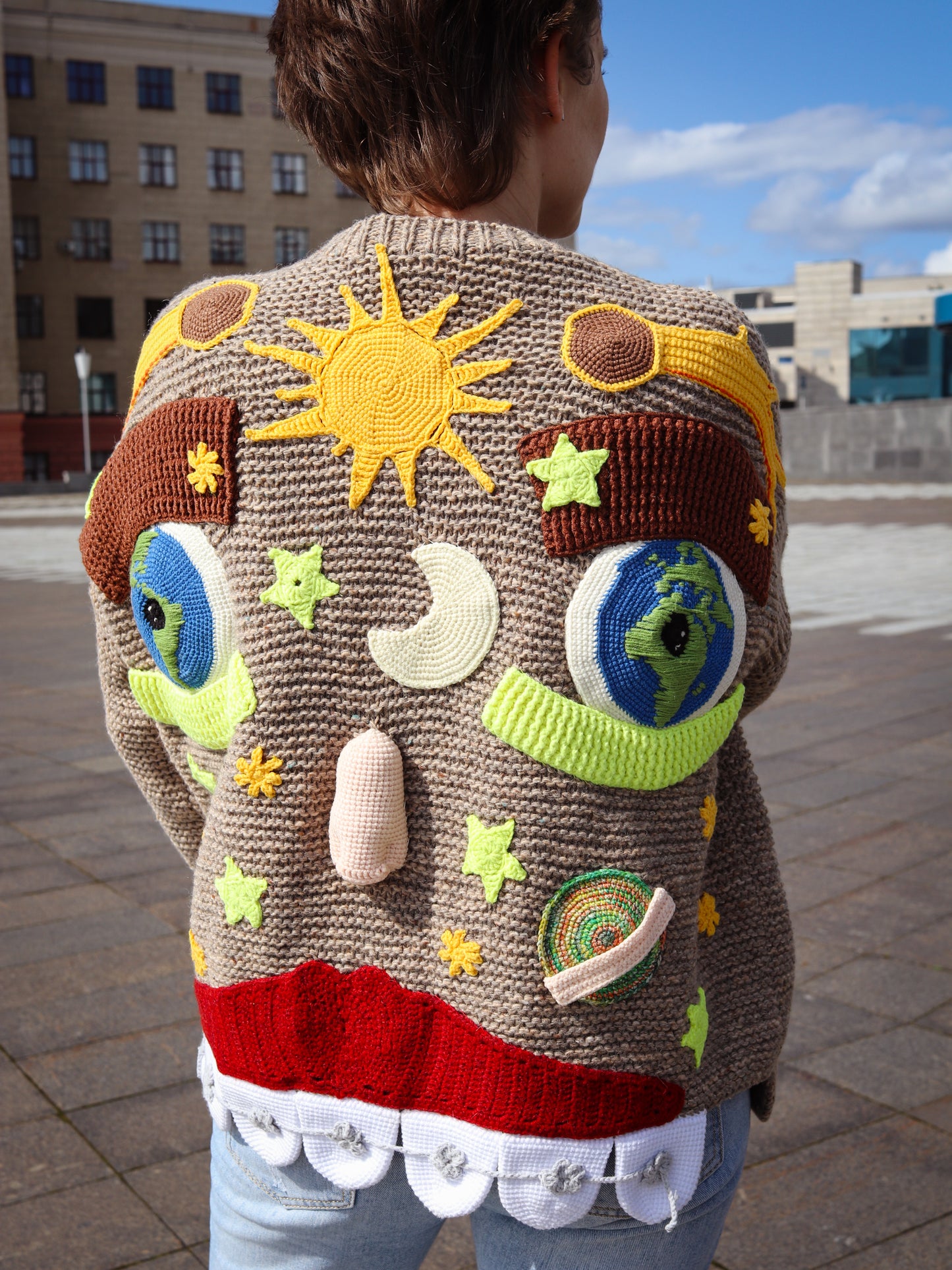Person wearing a colorful sweater with solar system designs outdoors.