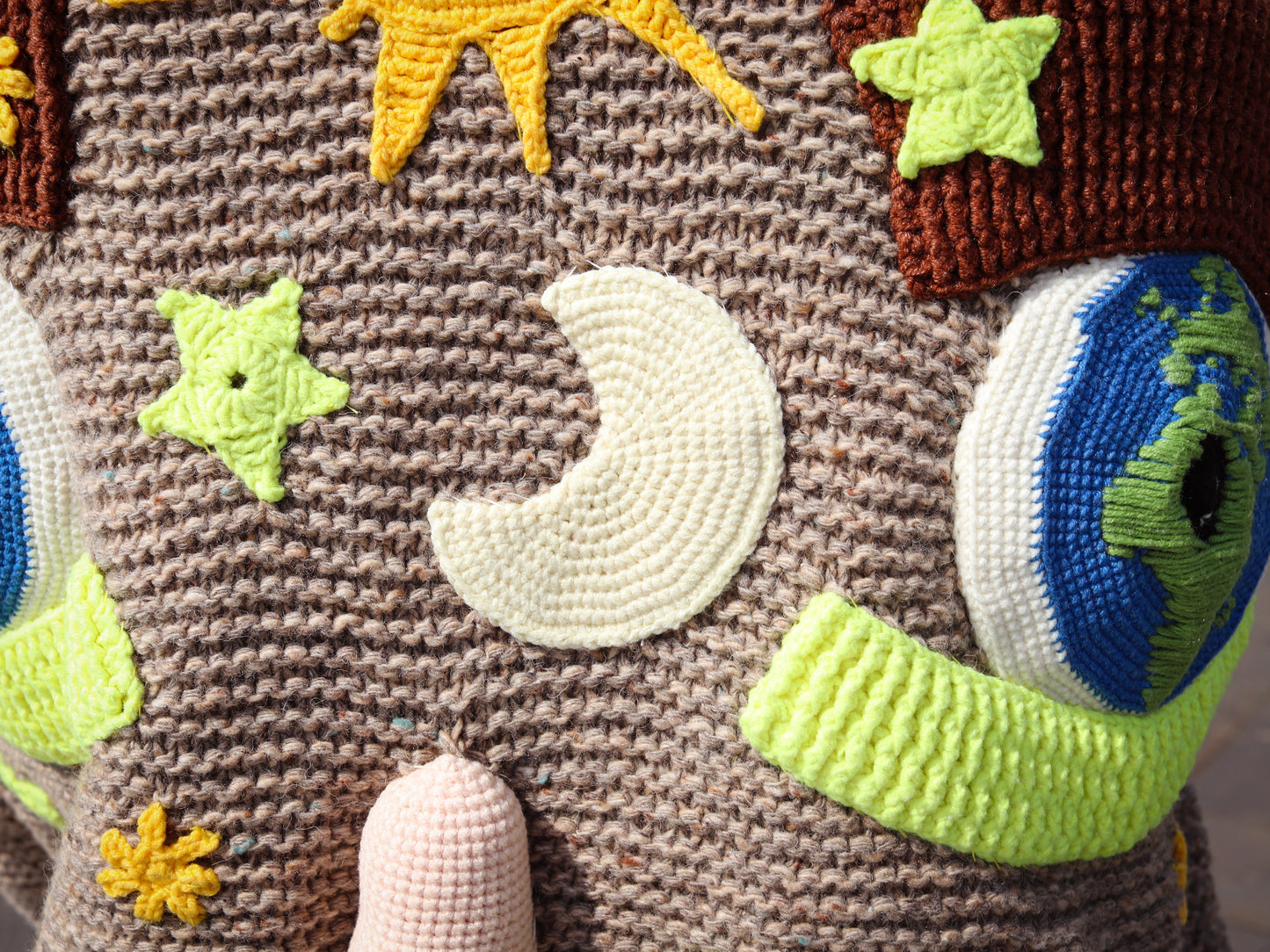 Close-up of a textured fabric with embroidered elements including stars, a moon, and planets.