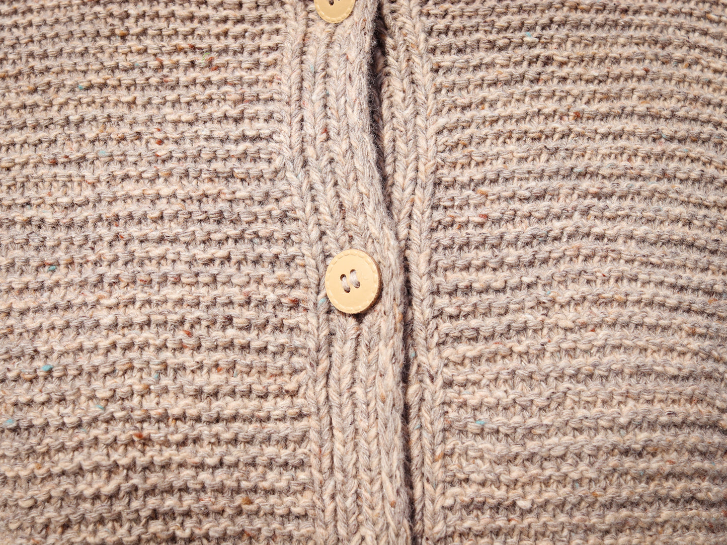 Close-up of a beige knitted cardigan with buttons