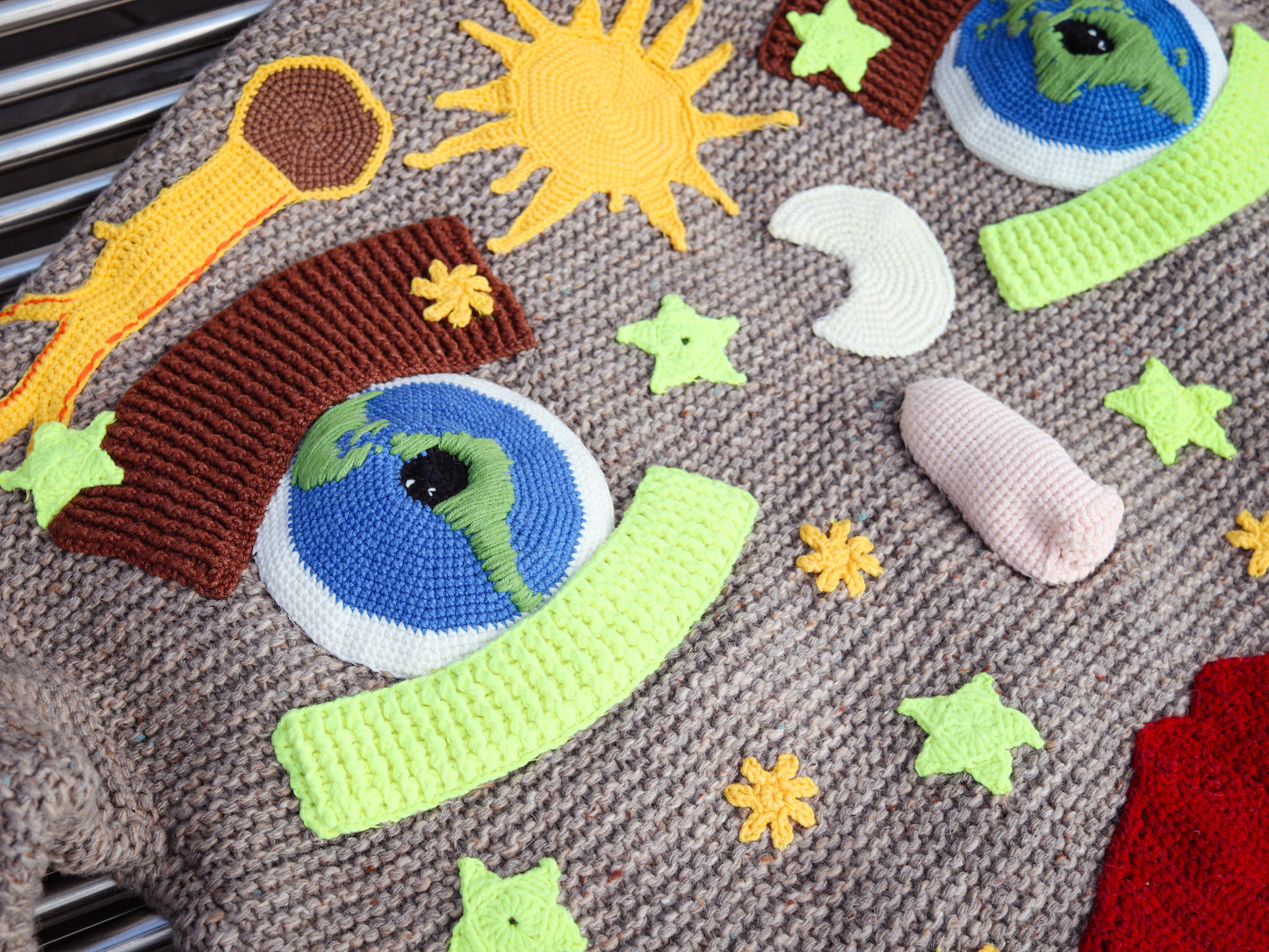 Crocheted solar design elements on a textured surface o a knit cardigan