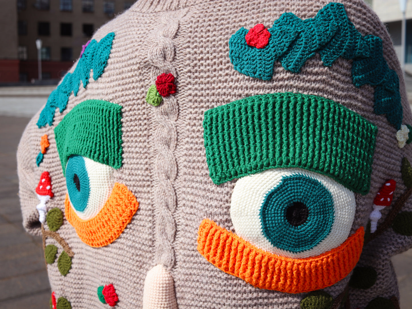 Close-up of a textured fabric with colorful eye-like elements and a face.