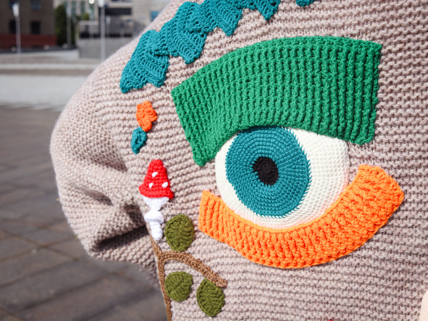 Close-up of a knitted item with a colorful eye design on a textured surface.