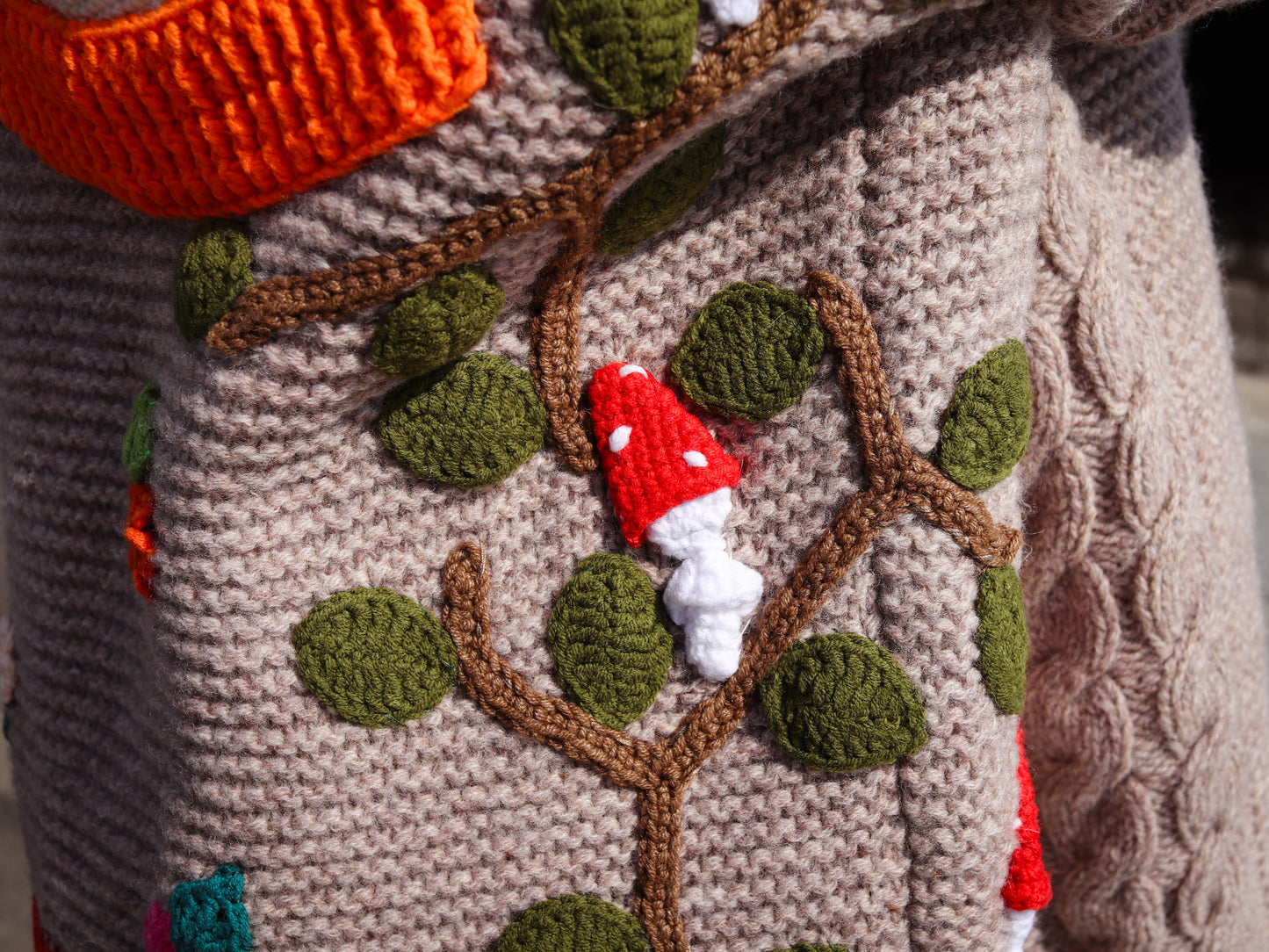 Close-up of a knitted or crocheted garment with a tree design featuring a mushroom.