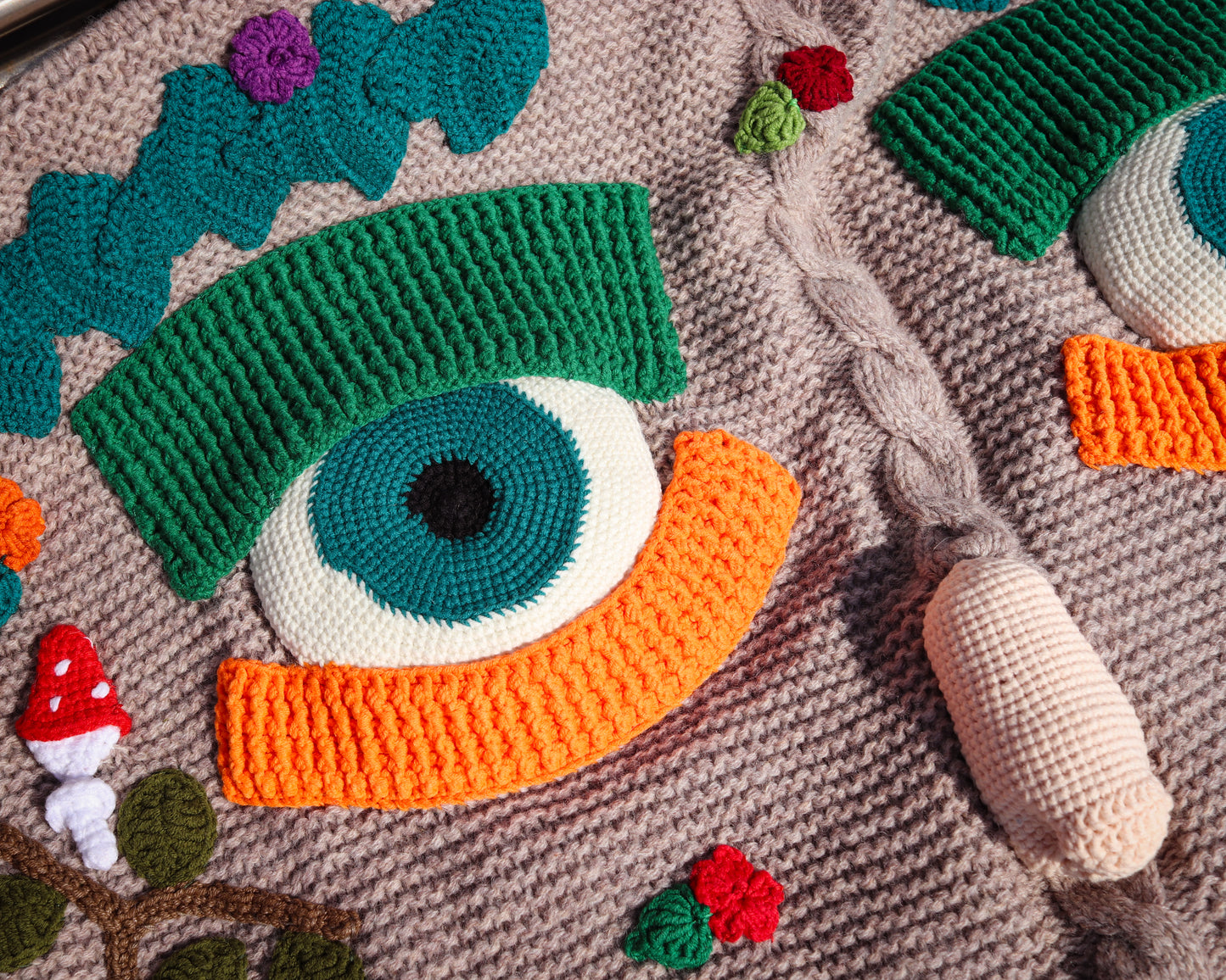 Crocheted eye design on a textured fabric background