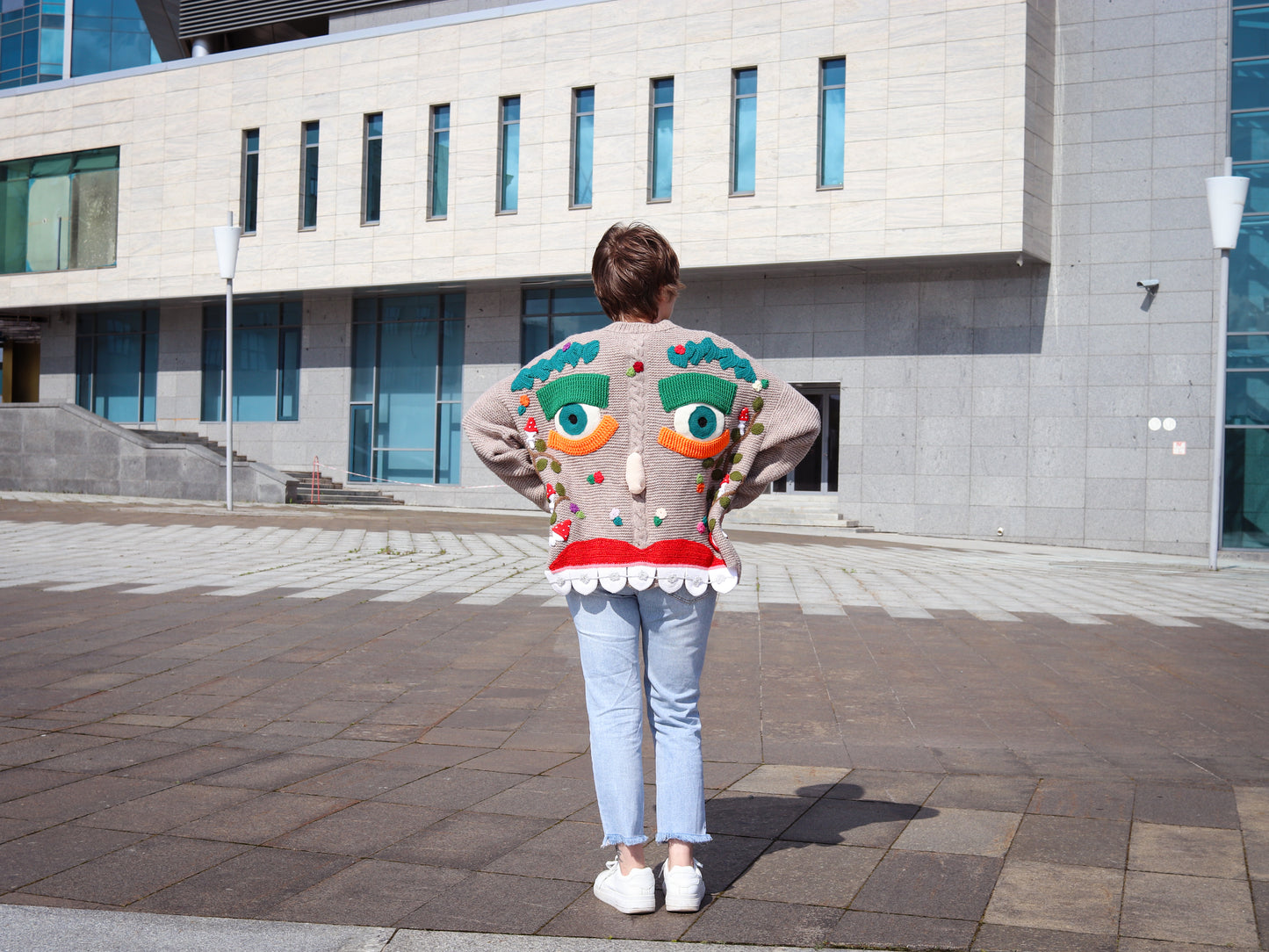 Person wearing a unique sweater with a colorful design in an urban setting