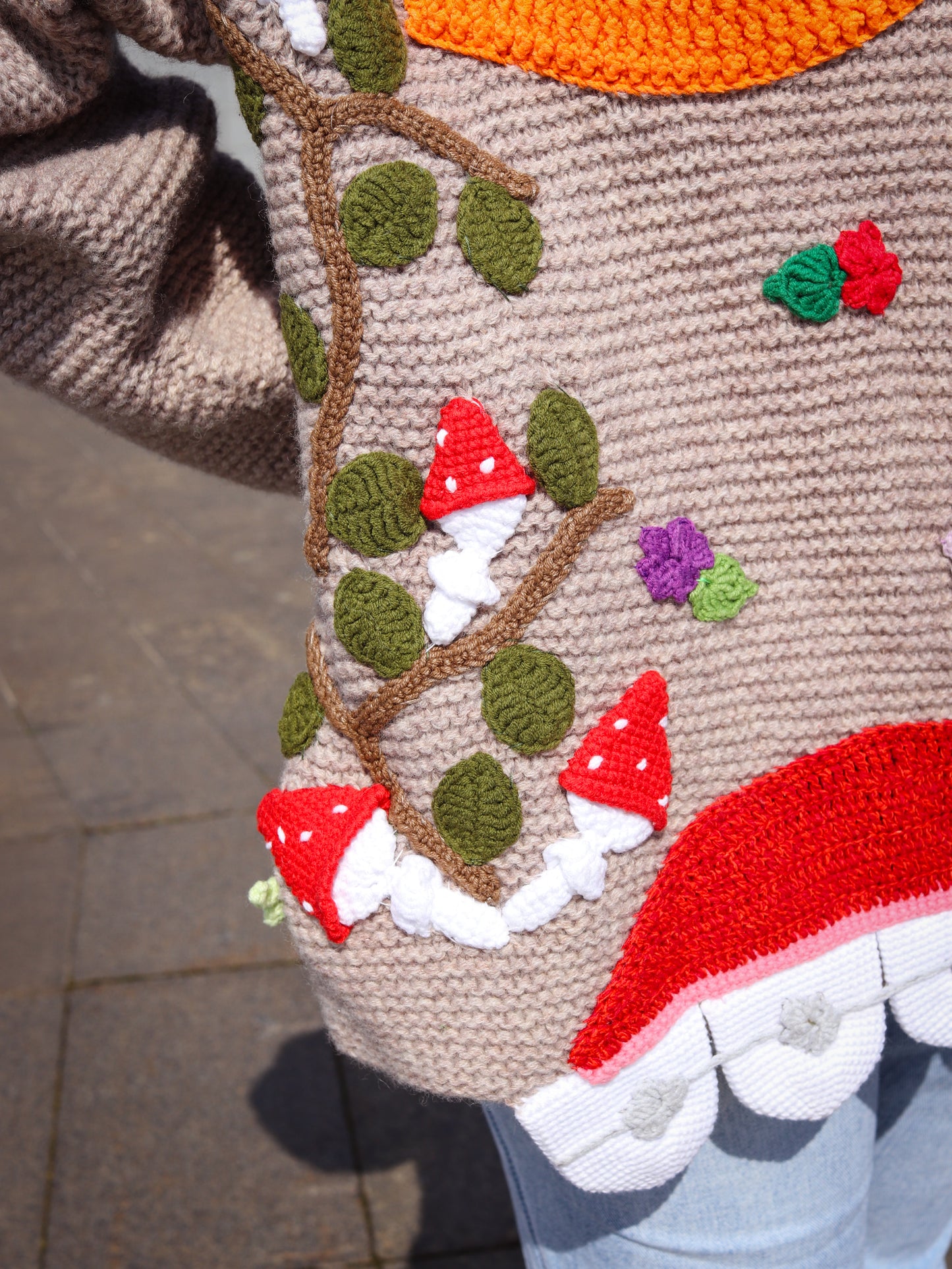 Close-up of a knitted or crocheted garment with mushrooms and leaves design.
