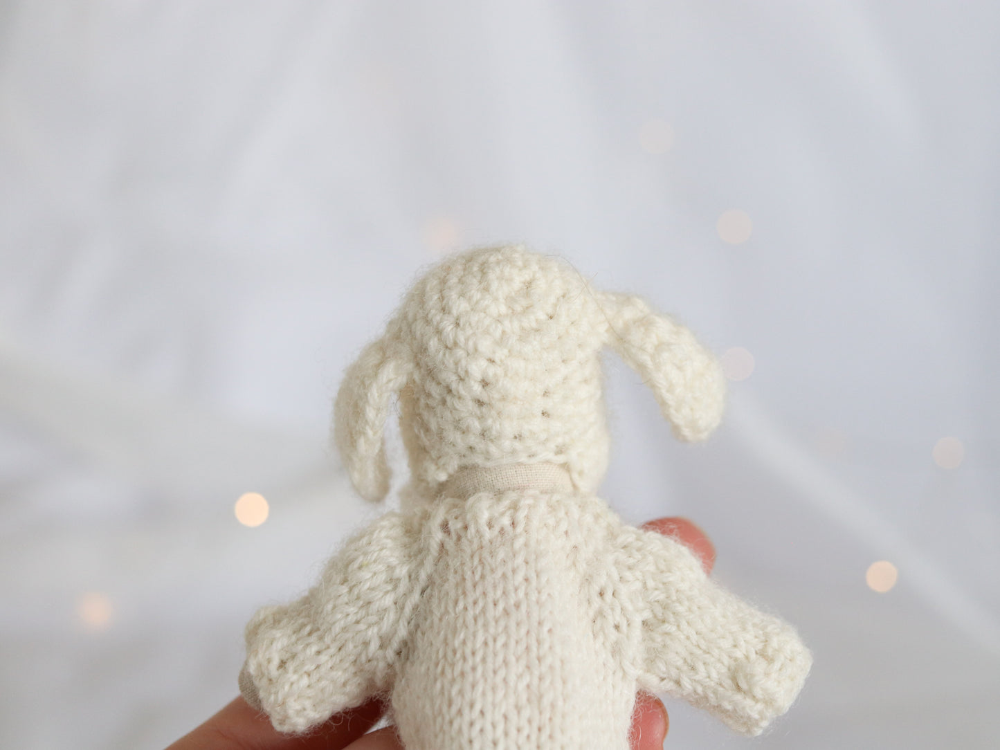 Handmade knit Maileg Mouse sweater held against a light background