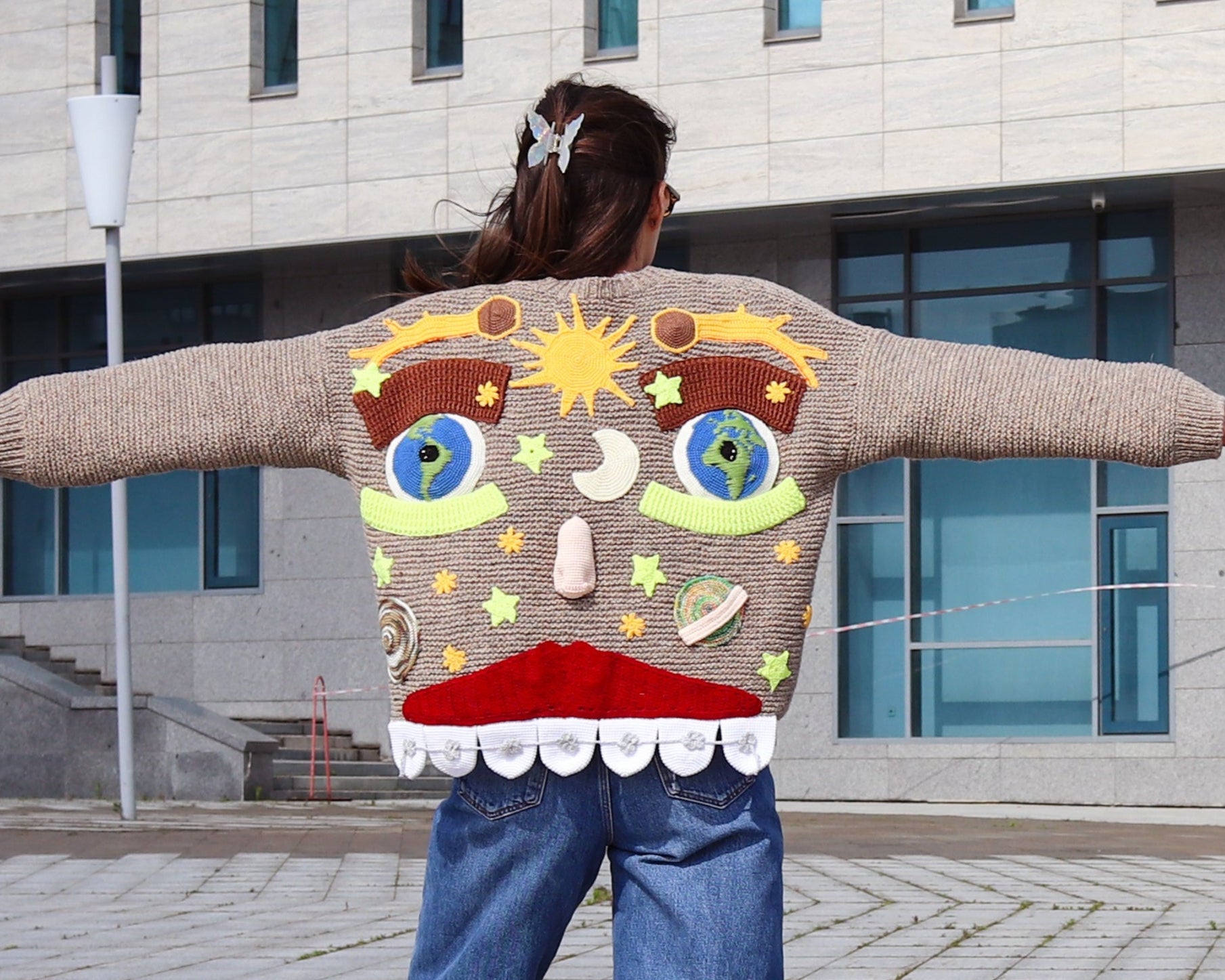 Hand-knitted cardigan with whimsical smiling face and eyes