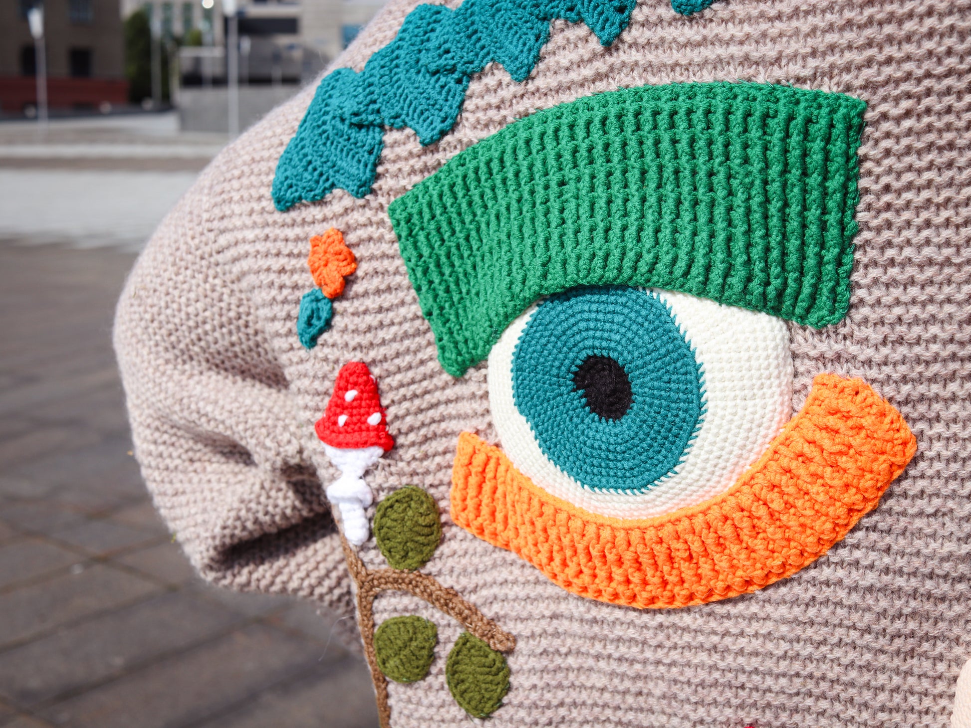 Close-up of a knitted item with a colorful eye design on a textured surface.