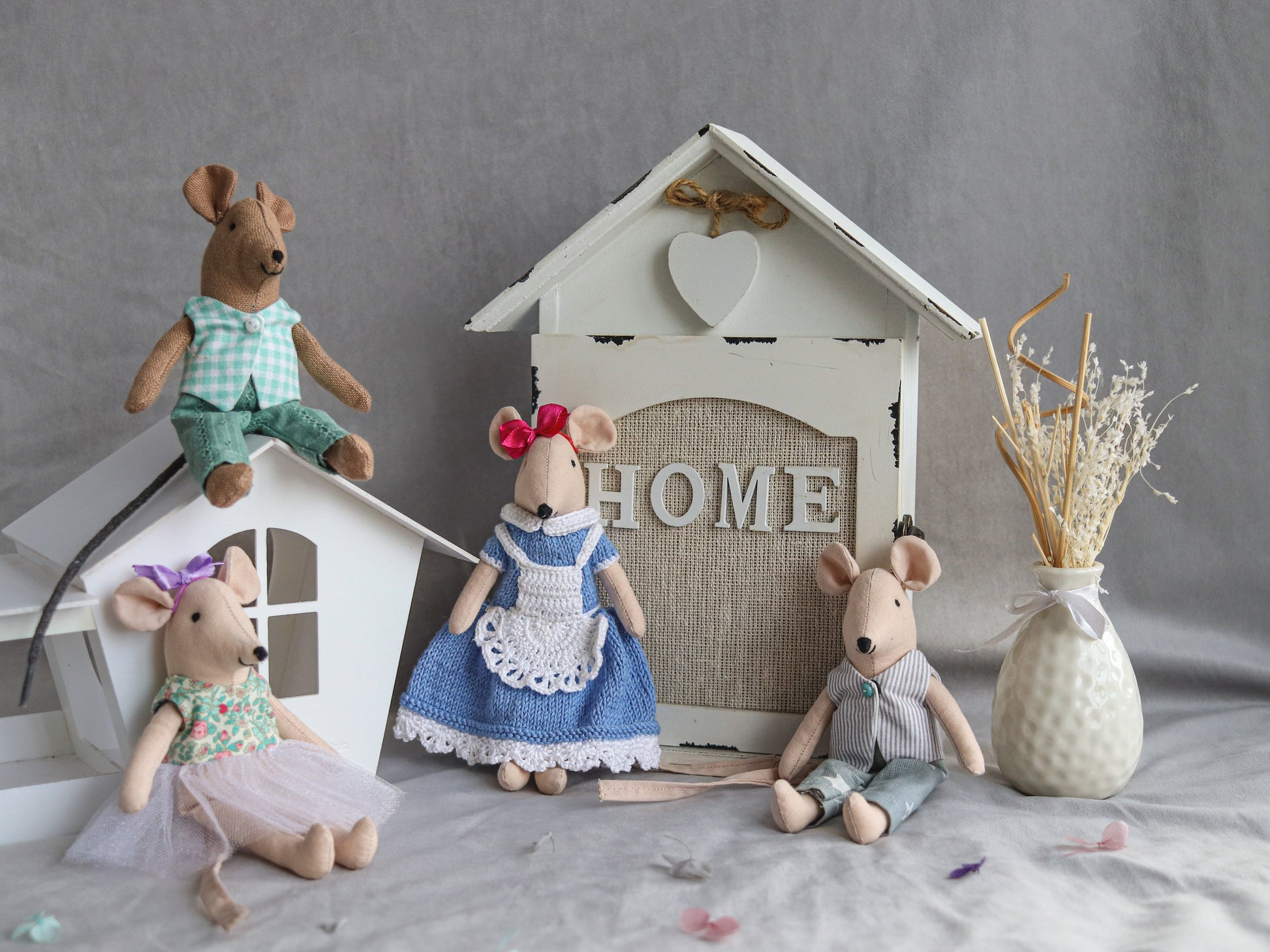 Four toy mice in front of a small house with 'HOME' written on it, on a gray surface.