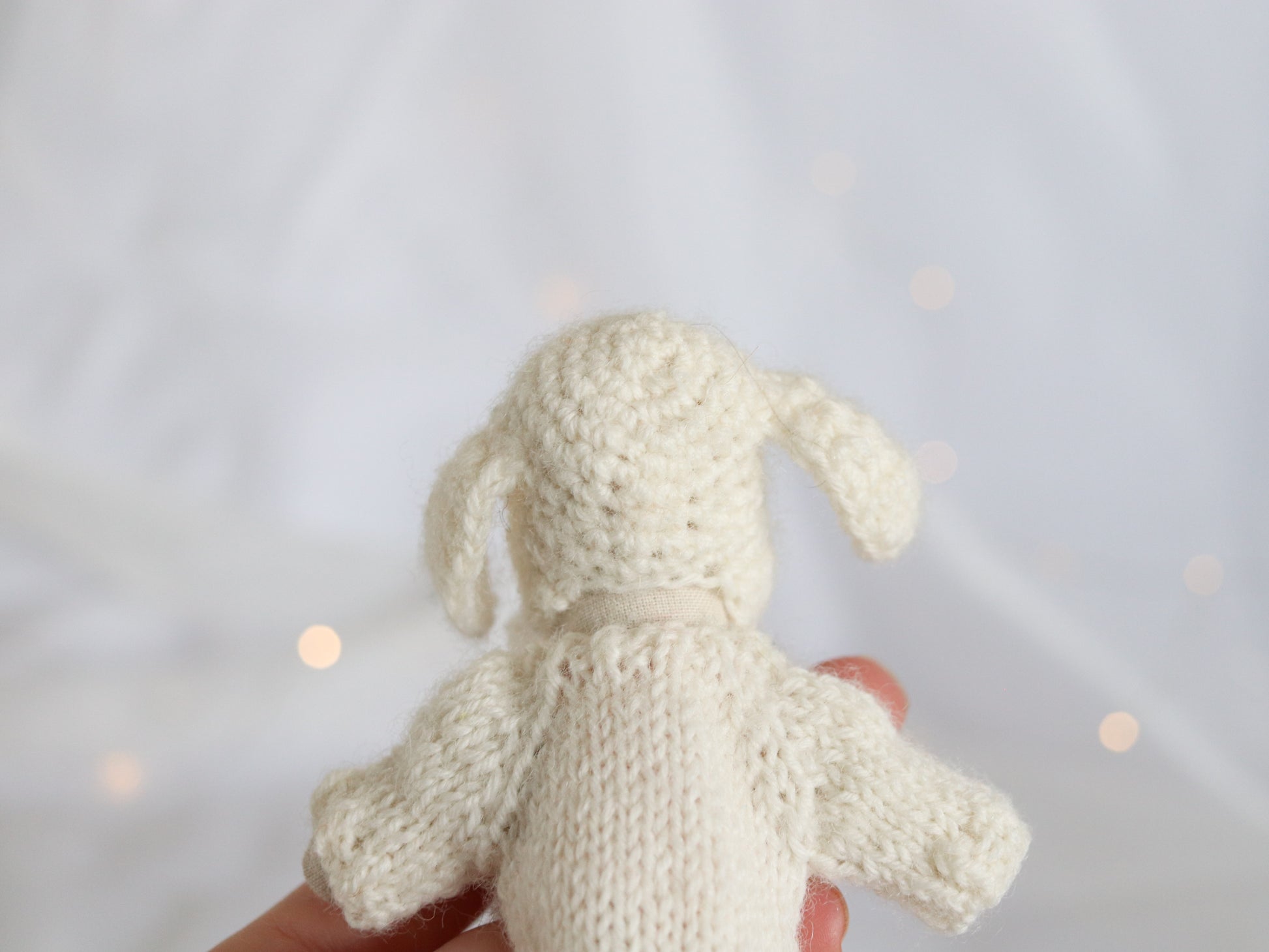 Handmade knit Maileg Mouse sweater held against a light background
